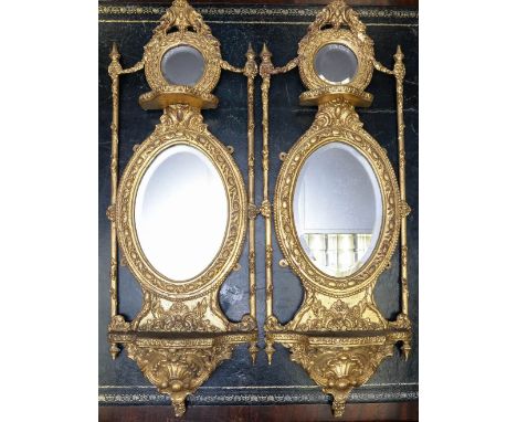 A pair of 19th century gilt framed mirrors, each with an upper section with a carved pediment over a small circular mirror wi