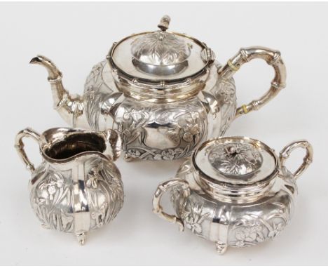 A Chinese silver three piece tea service, circa 1880, comprising tea pot, sugar basin with cover and milk jug, each embellish