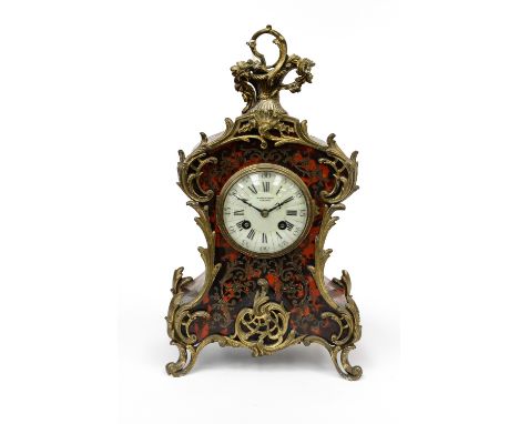 A French boullework bracket clock, c.1870, of Rococo design, cast brass finial and scroll mounts, the dial with retailer's ma