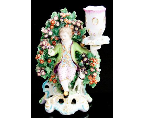 A Derby figural candlestick of a shepherd with dog seated before bocage, supporting a reticulated sconce, on a Rococo scroll 