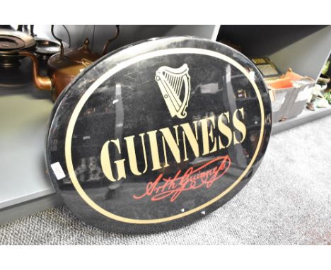 A oval Guinness advertising sign having gold coloured lettering on a black ground, w61cm
Condition report: Needs a plug. Some
