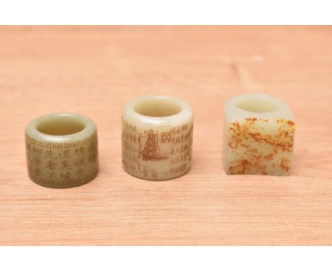 A group of three Chinese greenstone/jade/nephrite archers rings, two having inscribed text, one with figural depictions,