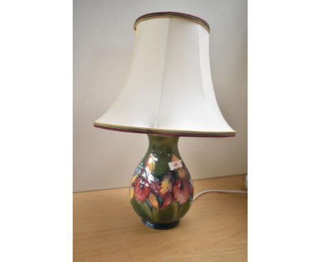A Moorcroft pottery Iris pattern table lamp of baluster form, decorated with floral patterns on a green glaze ground, having 