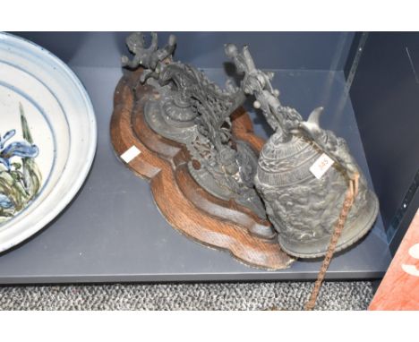 A Victorian/Edwardian oak mounted cast brass door bell, the putto surmounted pierced scrolling bracket suspending a bell cast