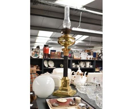A brass Corinthian column oil lamp having glass chimney and circular shade, the body decorated with black alloy diamond patte