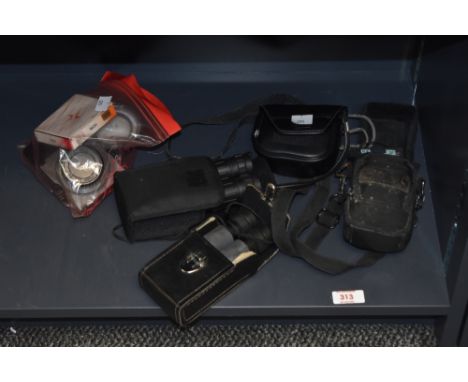 A selection of photographic lens filters, three small pairs of binoculars, and a Lumix digital camera
