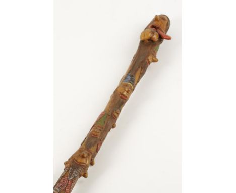 A FOLK ART WALKING STICK carved and coloured with various comic faces, the uppermost with mouth open and tongue extended, 38"