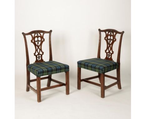 A PAIR OF GEORGE III MAHOGANY DINING CHAIRS with "Chippendale" style pierced and leaf-carved back splats, above overstuffed s