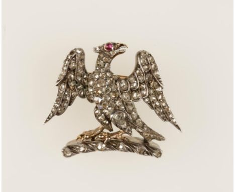 A DIAMOND EAGLE BROOCH, the bird with displayed wings and perched on a curved rockwork base set with numerous old-cut diamond