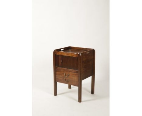 A GEORGE III MAHOGANY BEDSIDE COMMODE, the rectangular top with raised border and pierced hand holds above a tambour front an