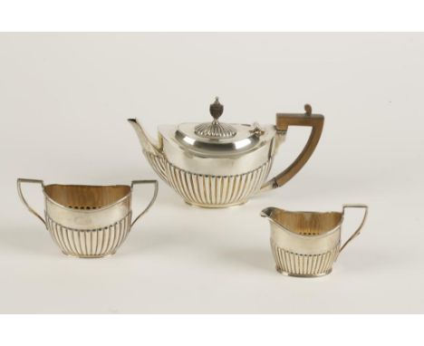 A VICTORIAN AND LATER MATCHED THREE PIECE TEA SET of oval form with part fluted decoration and angular handles, the teapot by