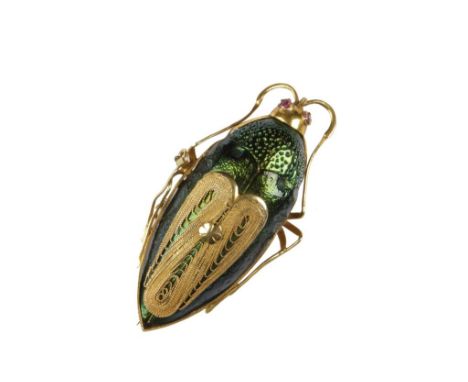 A SCARAB BEETLE BROOCH, the green enamel body overlaid with unmarked yellow metal wings, legs and head, with red stone eyes, 