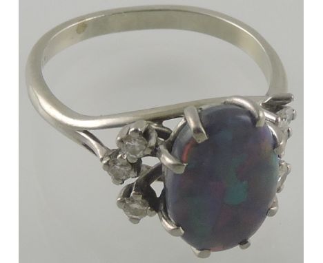 A black opal dress ring, the oval cabouchon stone approx 1.75ct flanked by 6 brilliant cut diamonds of 0.15ct in an 18ct whit