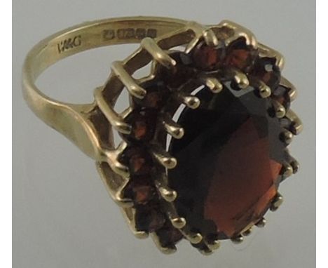 A garnet cluster dress ring with large central oval faceted stone claw set in a 9 carat band