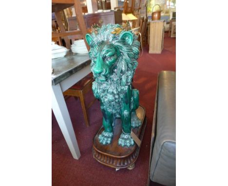 A pair of large green glazed ceramic lions, in seated position, with gilt metal crowns, raised on mahogany stands having circ