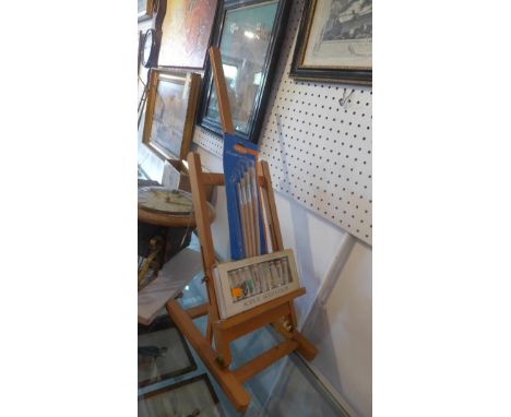 A table top artist easel with acrylic paint and brushes 