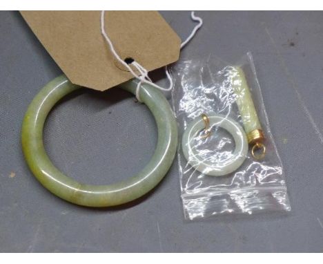 A Jade ladies bangle along with two Jade pendants, one being of oval form the other cylindrical, both having yellow metal mou
