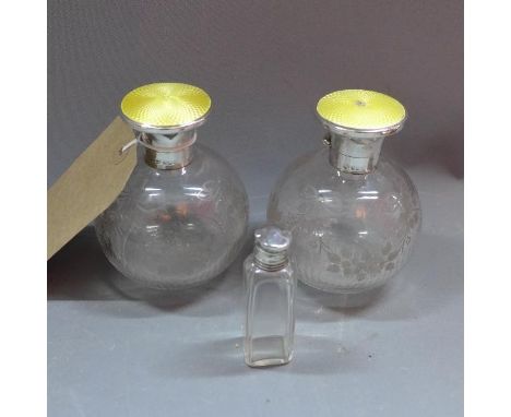 A pair of acid etched scent bottles, with silver a guilloche enamel tops, together with one other silver topped scent bottle 