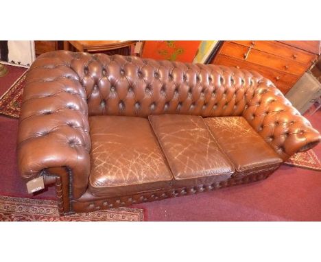 A mid 20th century Chesterfield three seater sofa, with brown leather button back upholstery, raised on castors 