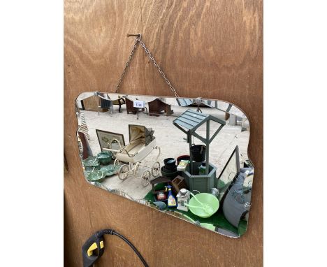 AN ART DECO UNFRAMED BEVELED EDGE MIRROR WITH CURVED DESIGN, HANGING CHAINS AND DECORATIVE CLIPS 