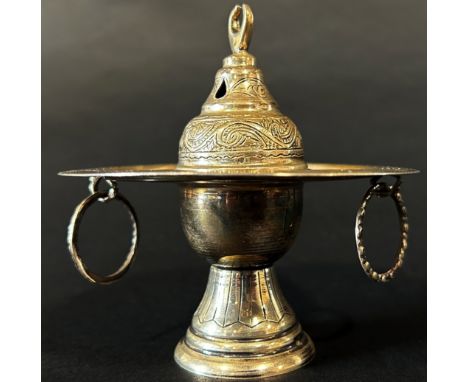 An Egyptian silver metal incense burner with ring handles below the dish and bowl and a pierced cover, 11cm high, in a blue d