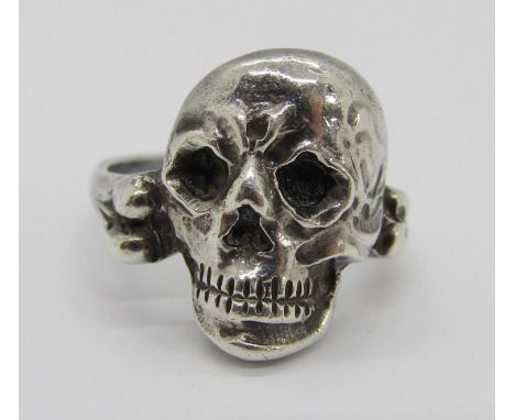 An unusual antique French silver ring in the form of a human skull, the shank forming a bone, indistinctly marked to reverse,