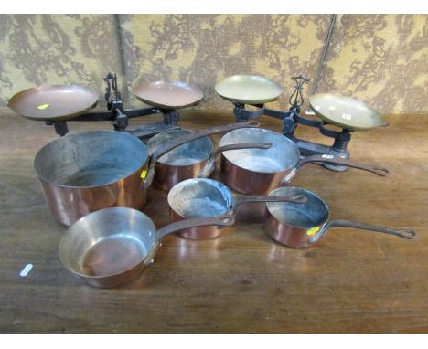 Two sets of cast iron balance scales with copper and brass pans, and six graduated 19th century copper and iron saucepans 