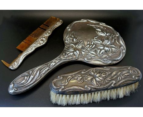 A silver Art Nouveau hand mirror with all over floral pattern, Chester 1909, maker J &amp; R Griffin, together with a comb an