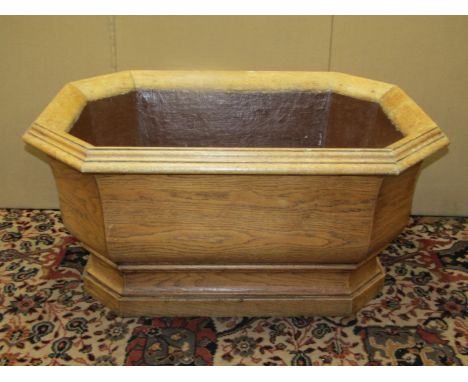 A large 19th oak century pale oak planter to an 18th century design of elongated octagonal form raised on a moulded plinth wi