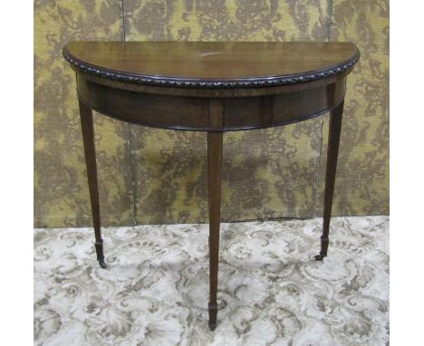An Edwardian mahogany demi-lune fold over top card table in the Georgian style raised on square tapered supports and spade fe