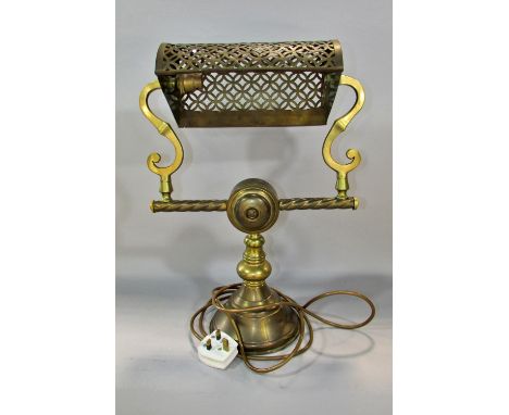 An early 20th century American brass desk lamp with pierced adjustable shade held by S supports and a central Dolly switch on