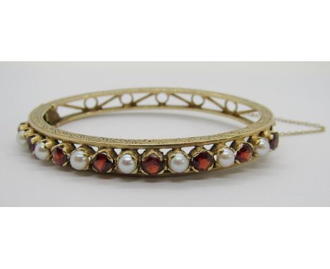 Vintage yellow metal hinged bangle set with eight garnets and seven pearls, with engraved scrolled decoration, 22.8g 