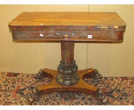 A Regency rose wood fold over top card table raised on an octagonal pillar with foliate column, the platform base with lions 