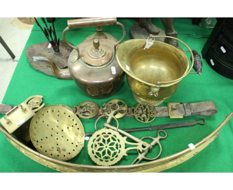 A copper kettle, miniature brass coal helmet, martingale and horse brasses, beer skimmer, carriage clock, brass fender, horse