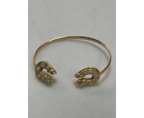 A diamond set hourseshoe torque bangle, horseshoes tested as 18ct gold, bangle tested as 9ct gold, weight 20g