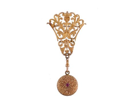 A ruby locket, the circular textured locket set with a circular cut ruby, suspended below an openwork scroll and foliate broo