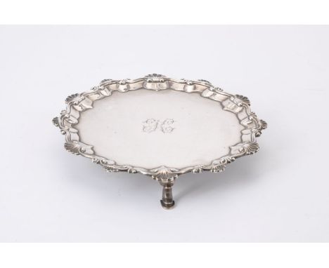 A George III silver shaped circular waiter by John Carter II, London, 1770, with a raised shell and scroll rim, on three scro