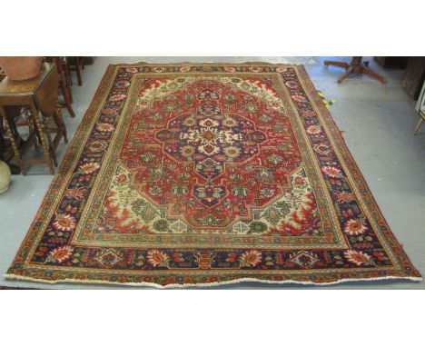 MIDDLE EASTERN HAND KNOTTED FOLIATE DESIGN RED GROUND CARPET with dark blue borders and cream ground spandrels on a red field