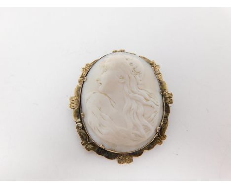 A Victorian yellow metal cameo brooch with an engraved scalloped border and carved shell cameo with classical female profile 