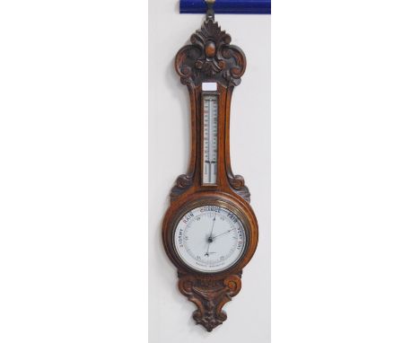 Edwardian oak banjo aneroid wall barometer with thermometer gauge above a circular dial, by T &amp; E Rhodes, Kendal, carved 