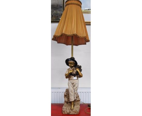 Goldscheider-style painted plaster figure table lamp modelled as a boy, painted in gold, cream and black, standing on a natur