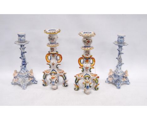 Two near-matching Rouen Faience candlesticks decorated with mythical masks and floral panels, 25cm high, together with a pair