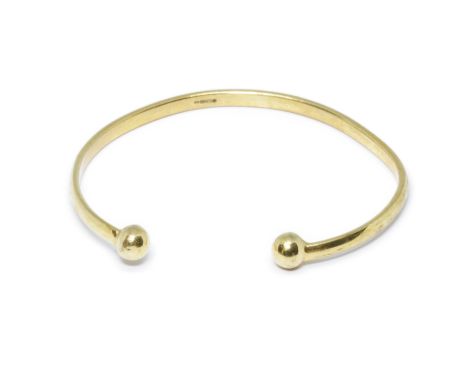 A 9ct gold torque bangle, International convention marks, width 56mm, weight 7.7g.