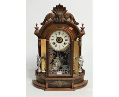 A late 19th century walnut cased mantel clock, the paper dial with Roman numerals, having eight day movement enclosed by a gl