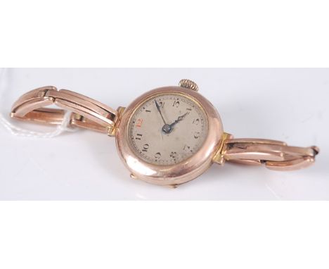 A 9ct yellow gold manual wind wristwatch, with round discoloured Arabic dial, attached to a spring metal bracelet with box cl