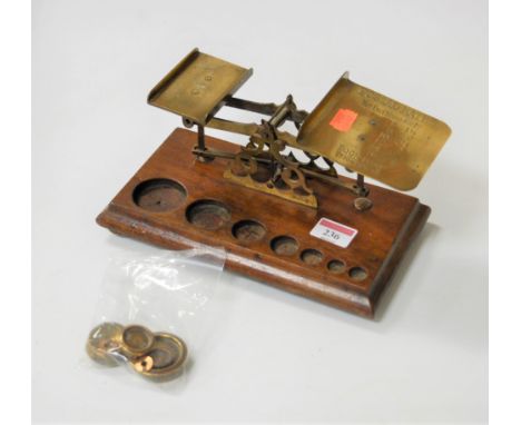 A pair of Victorian brass postal scales and weights on an oak plinth