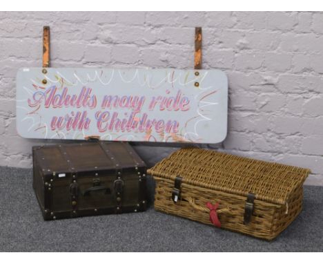 A double sided fairground sign along with a wicker picnic hamper and a carry case.