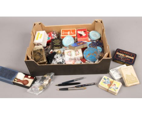 A box of collectables including playing cards, pens, costume jewellery, Wade whimsies, brass wall plaques.