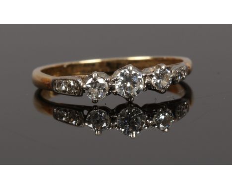 A mid 20th century three stone diamond ring with diamond set shoulders, principle stone approximately 0.12ct, unmarked.