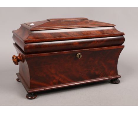 An early Victorian figured mahogany fitted tea caddy of sarcophagus form.